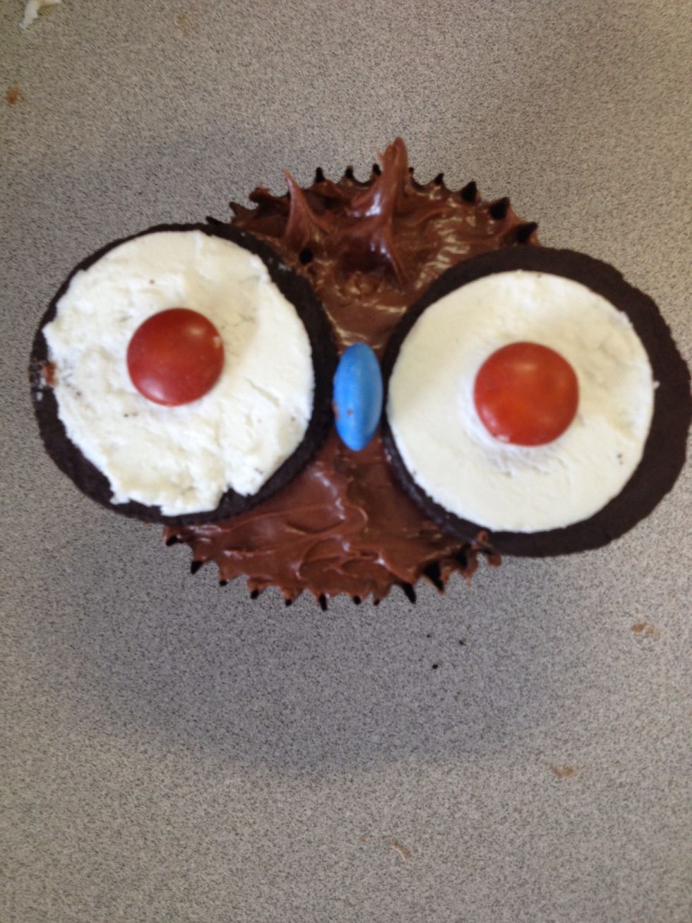 Press the biscuit with the MnM on it; onto the side of cupcake with the icing acting like a a glue