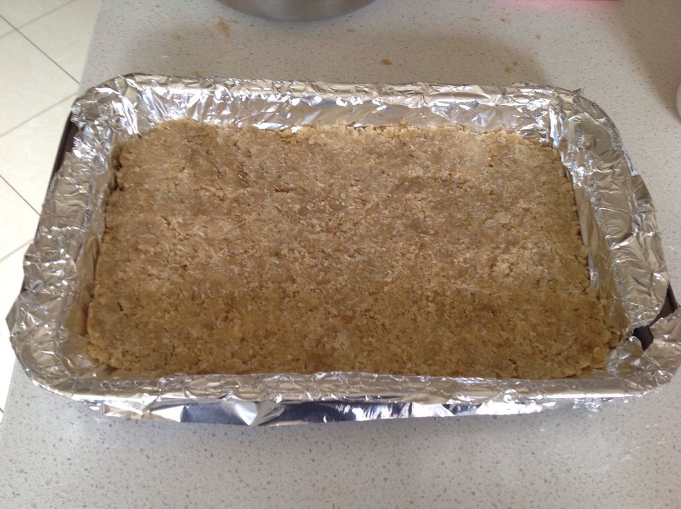 Press the mixture evenly onto the base of the prepared tin using the back of a spoon then bake for ten minutes and leave to cool.