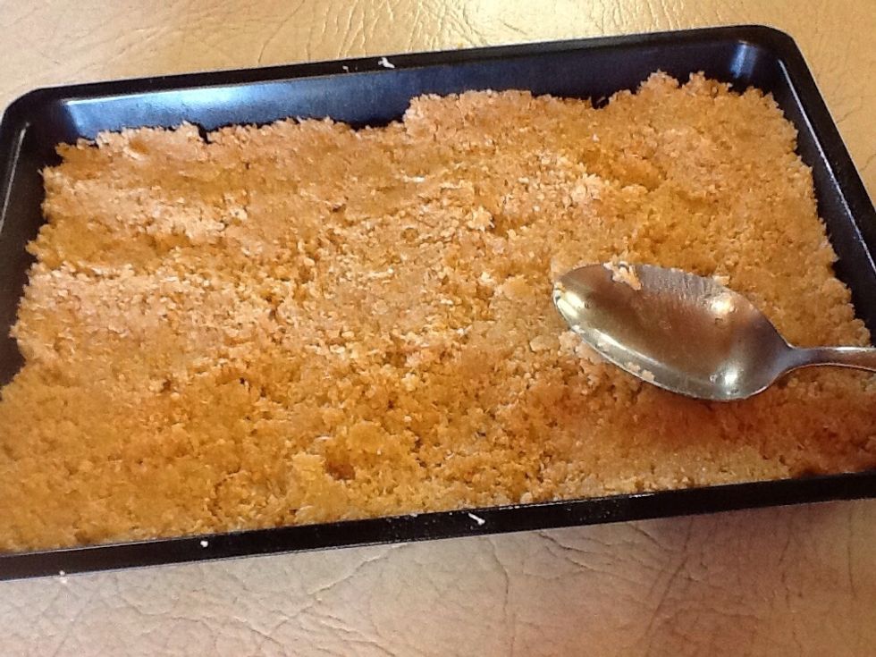 Press the mixture into the prepared baking pan. The back of a spoon or the base of a glass can be used to help press the mixture down firmly and smoothly.