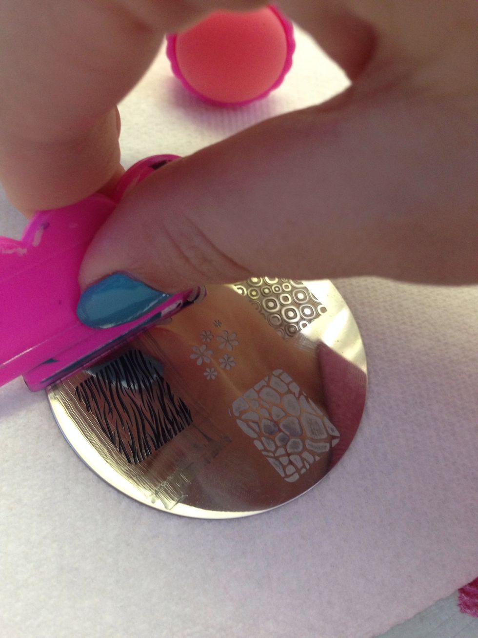 Press the scraper down hard and push across the design. Every crevice of the picture should fill with polish.