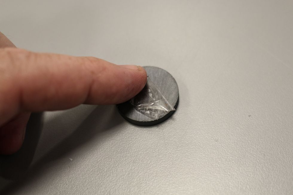 Press the sticky tape roll onto the magnet.