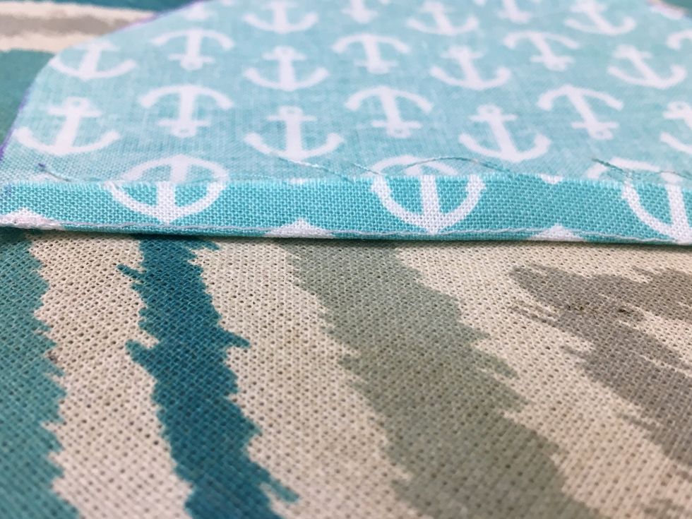 Press under 1/4" the flat edge of the half circle to the wrong side. Use the stitch line as a guide.  The stitching should be along the crease when pressed.