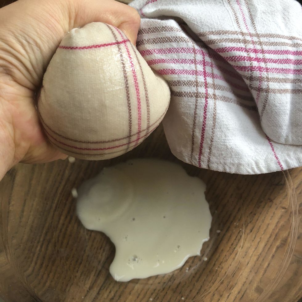 Presser la "pur\u00e9e" de manioc dans le torchon : le jus s'\u00e9goutte dans le saladier. Conserver ce jus.