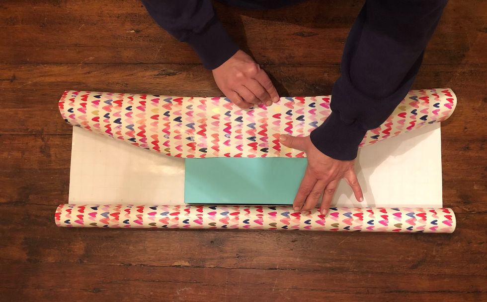 Pull one side of the paper to the middle of the present and create a crease by running your finger over the edges of the present.