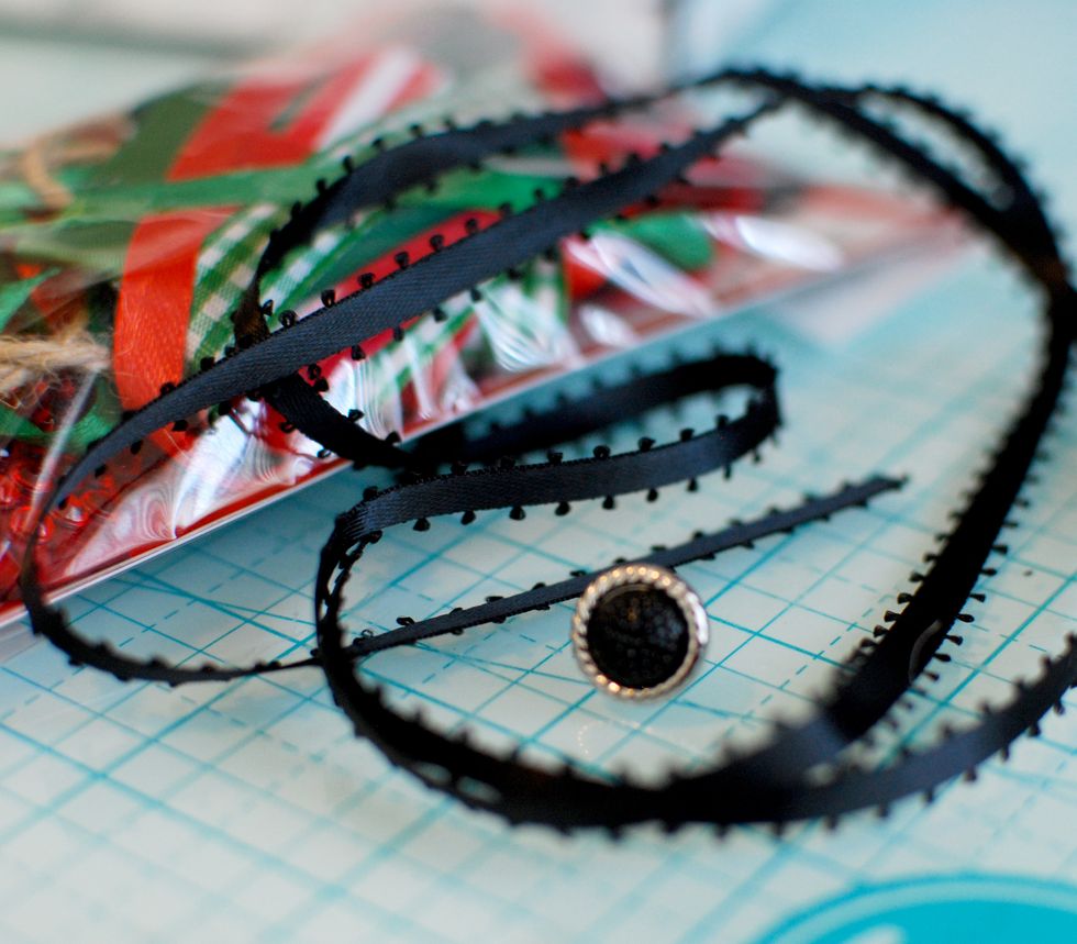 Pull out the black ribbon and black brad from the FotoBella Fiber & Embellishment Pack.