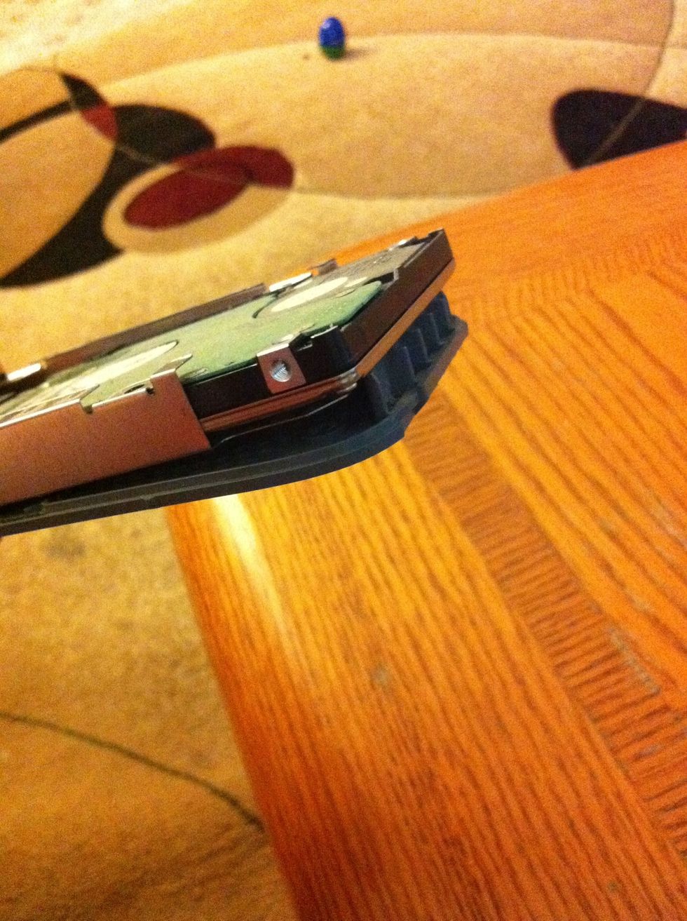 Pull the hard drive away from the connected cable. You have to slightly bend the gray holed plastic piece to slide the hard drive out as pictured.