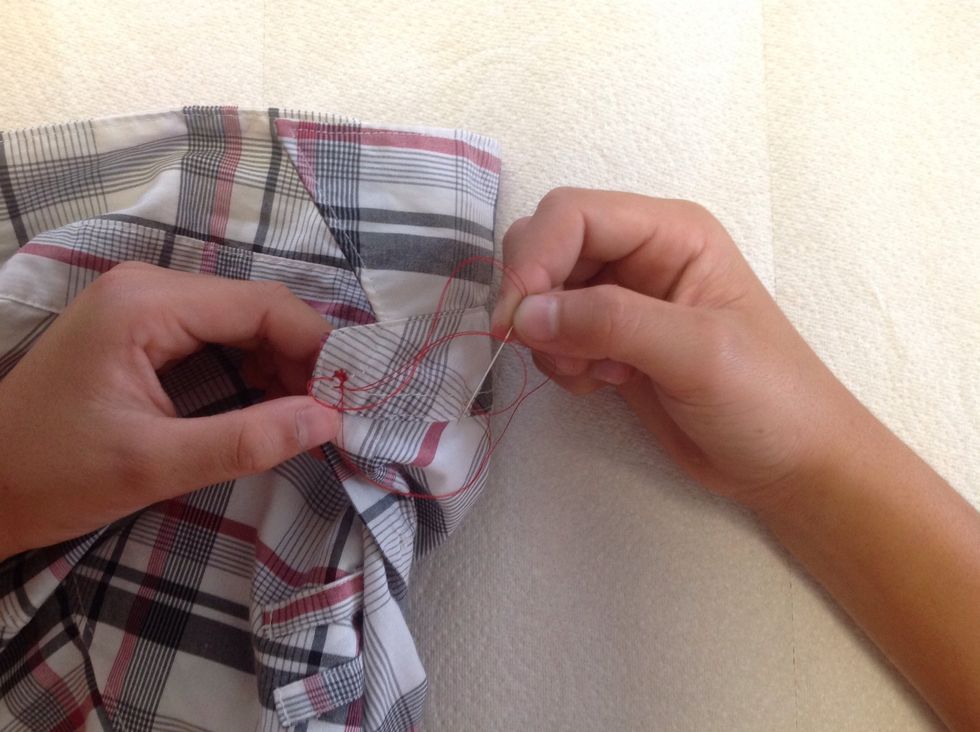 Pull the needle and thread a tiny bit out of the material and underneath the thread to make a knot.  Pull it tight to make the knot secure.