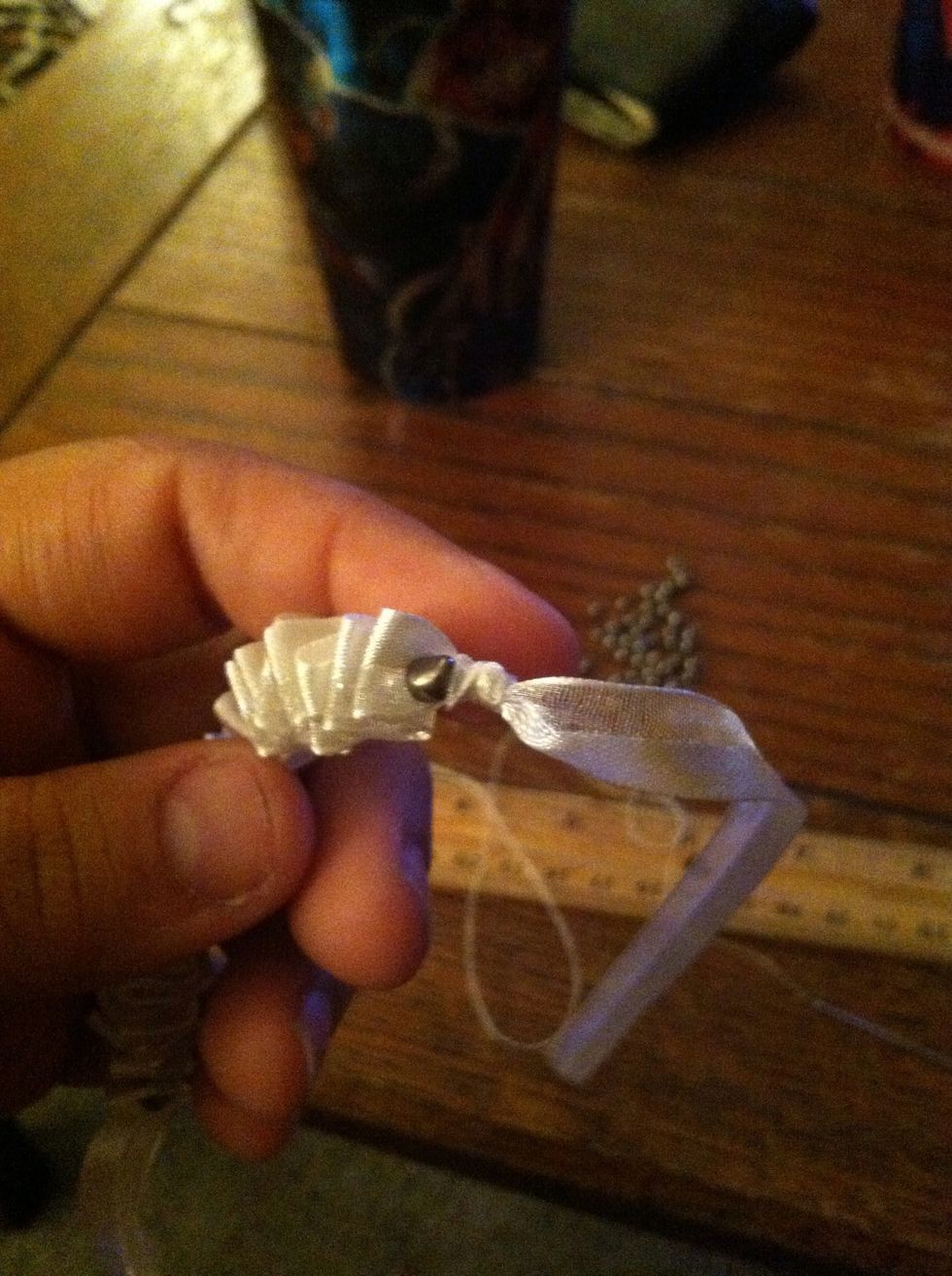 Pull the needle through creating a knot close to the bead. Tie it again if you'd like and trim off. Tie a knot in the ribbon close to the bass on both ends.