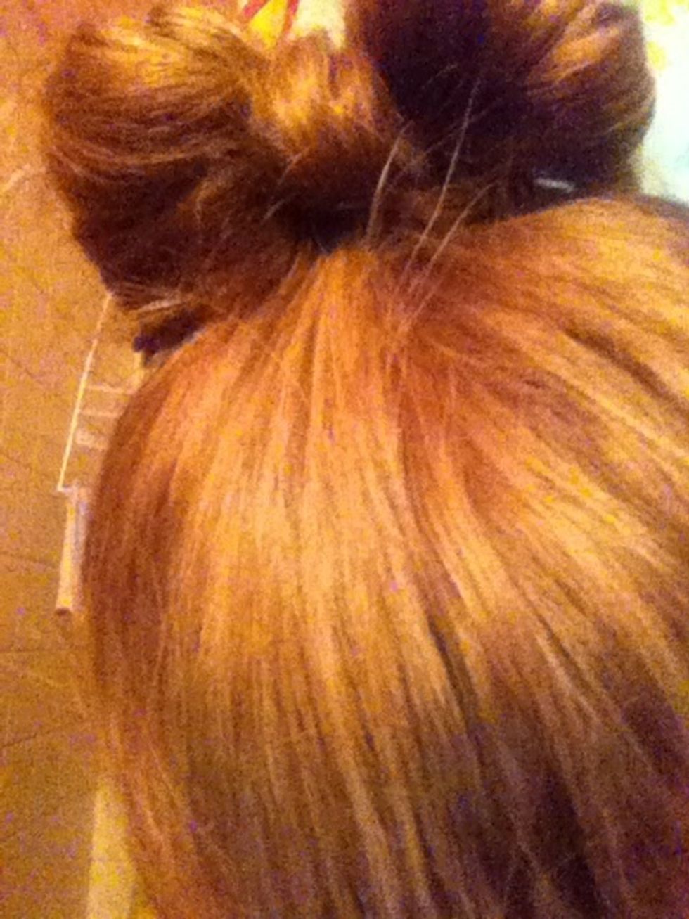Pull the piece of hair that was left out of the bun over the space where you split the hair. Pin it down in the back.
