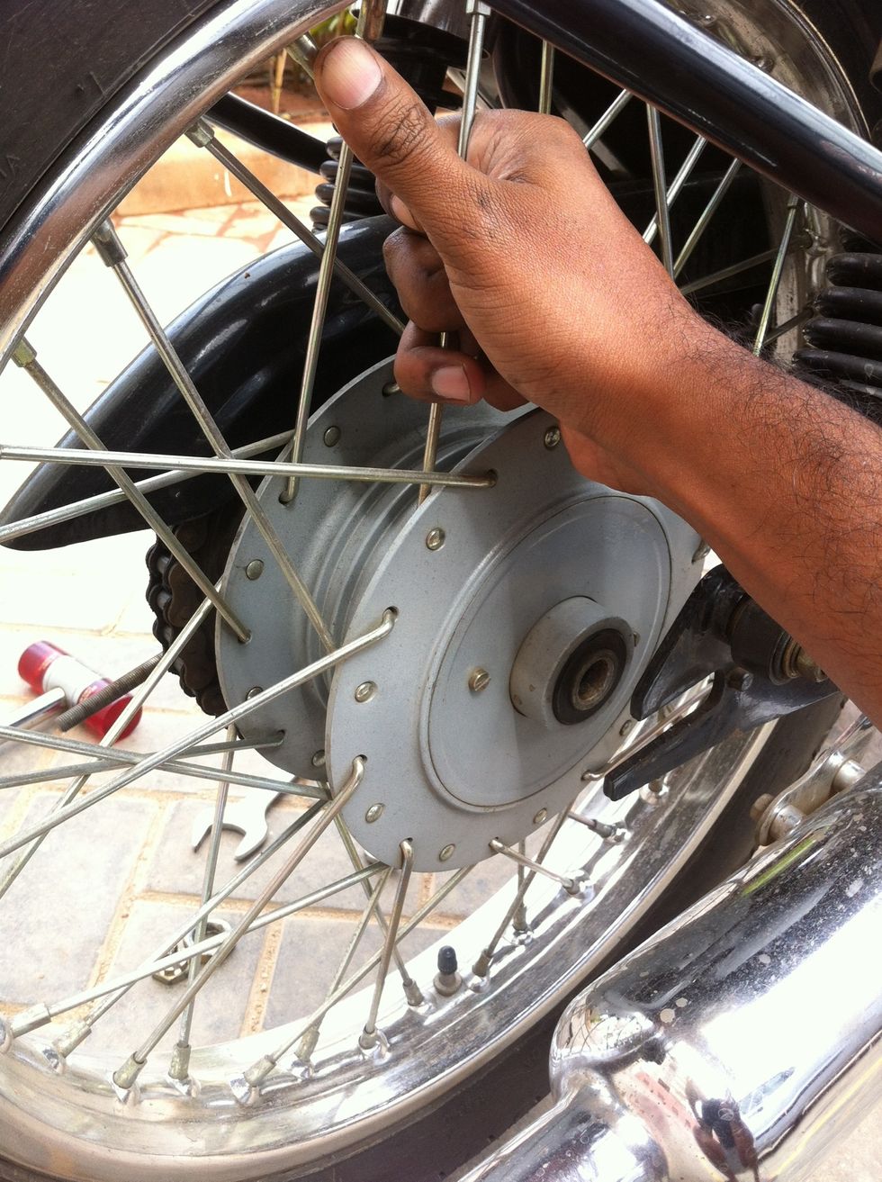 Pull the rear wheel out using both hands. ( See in image the stepped bush is still in place. Remove that prior to wheel handling and keep it along with the big spacer on the axle rod )