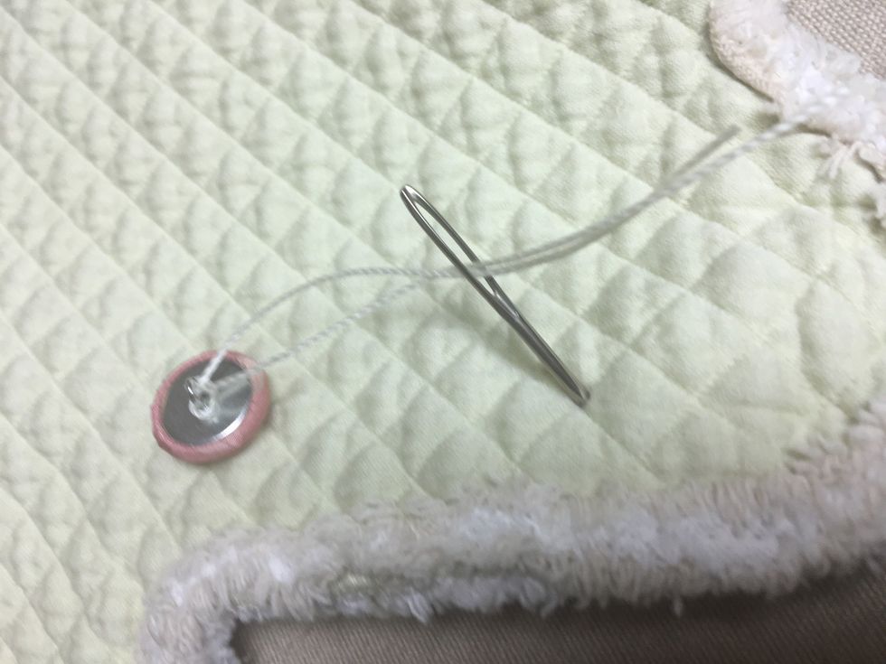 Pull the tufting twine, that is attached to the button (pink), through the fabric at the pencil mark to the contrasting side........
