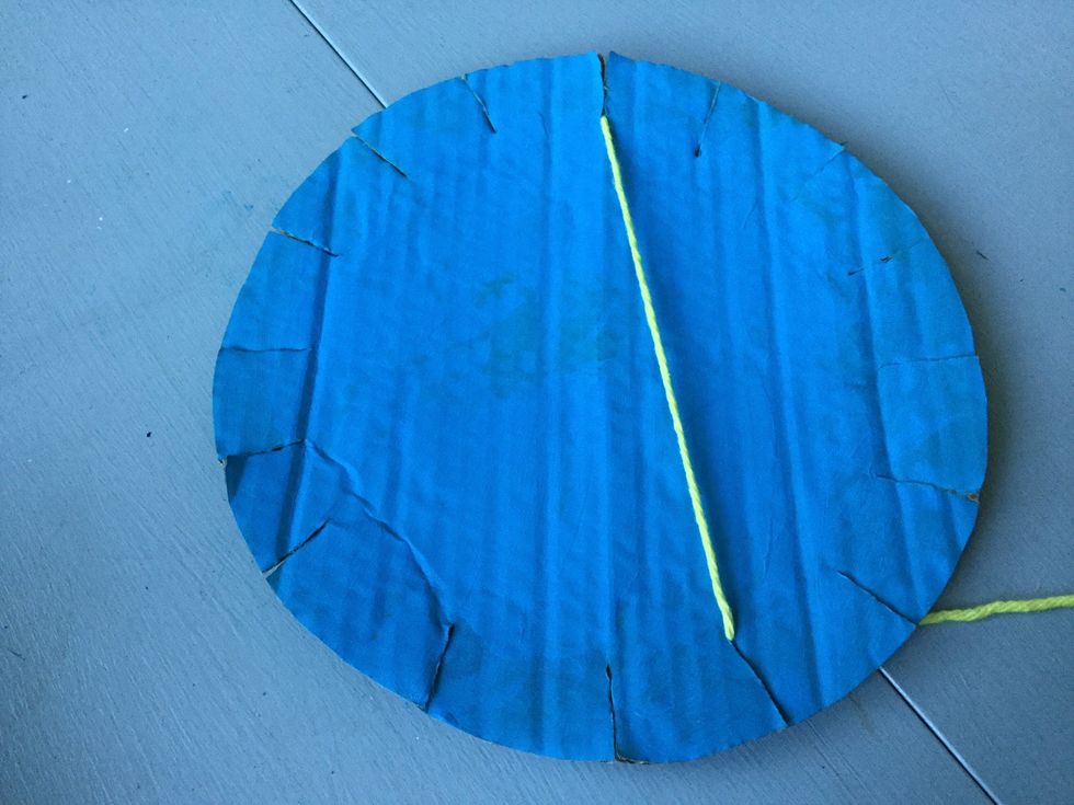 Pull the yarn across the cardboard and pull it through the slit diagonal from the first slit.  Wrap the yarn around the back of the cardboard