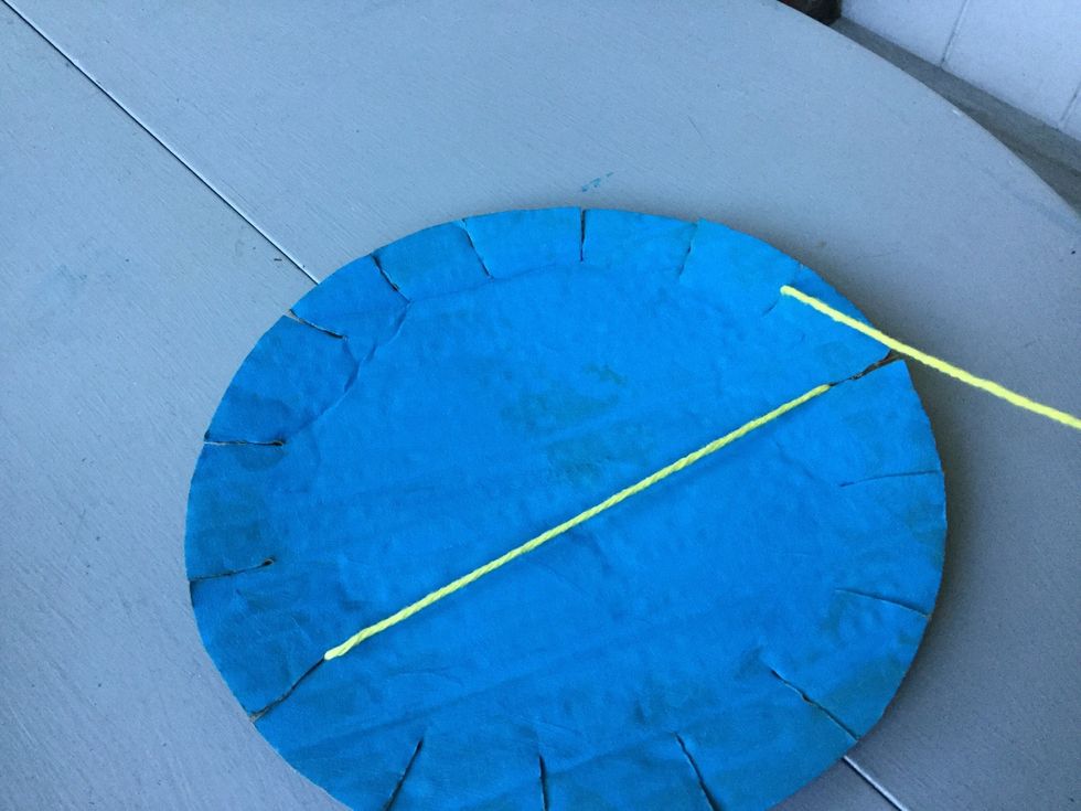 Pull the yarn through the slit to the left of the first slit, then pull the yarn across the cardboard