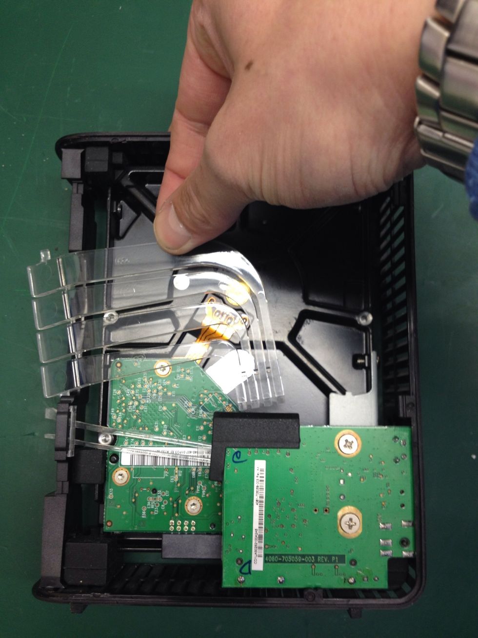 Pull this piece of transparent plastic away as show, releasing it from the rubber mount in the small raised PCB.