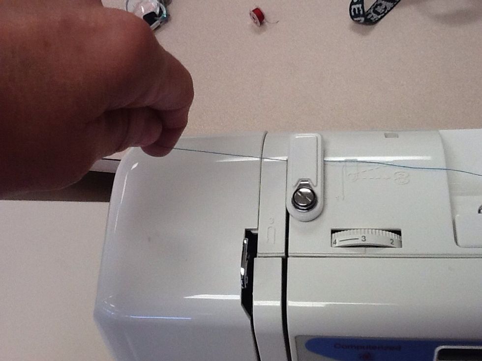 Pull thread under upper tension guide and then bring towards the front of the machine.