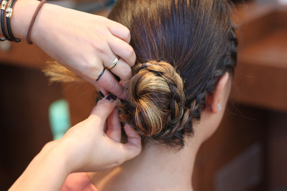 Pull up on different plaits of the braids from the bottom up to give it a relaxed feel. Then take the braids and twist them around the bun in opposite directions. Secure with more pins.