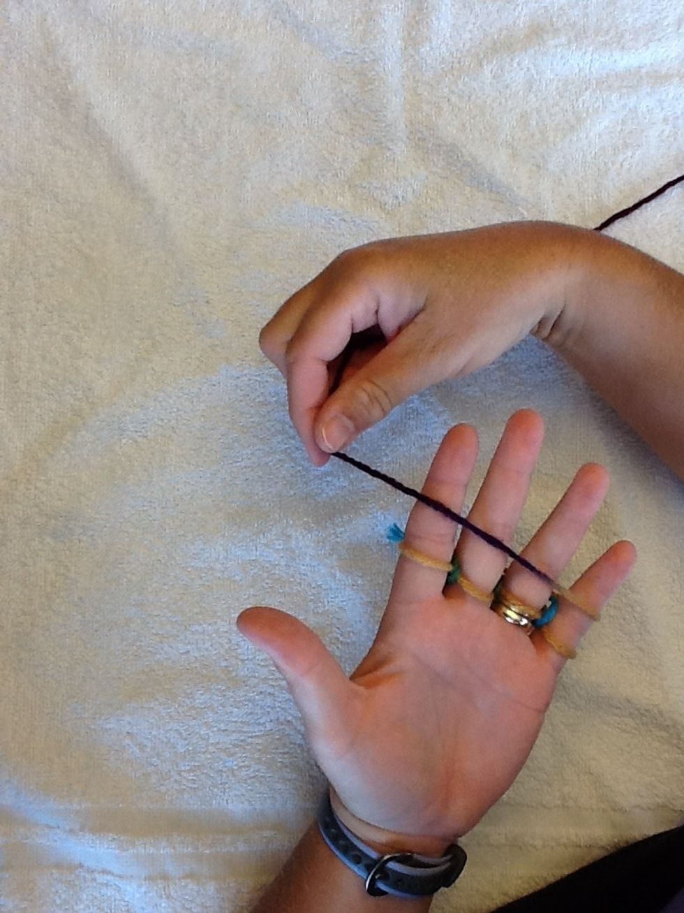 Pull yarn around the pinky and over all fingers, keeping this yarn above the others.