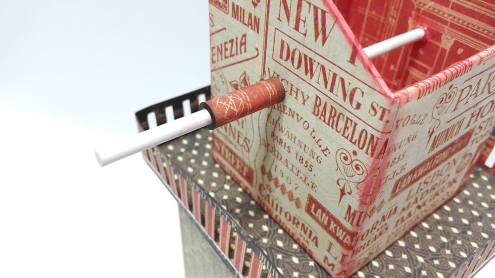 Punch holes on the top tower, put the candy stick through, close the end with another 4"x1" paper as shown.