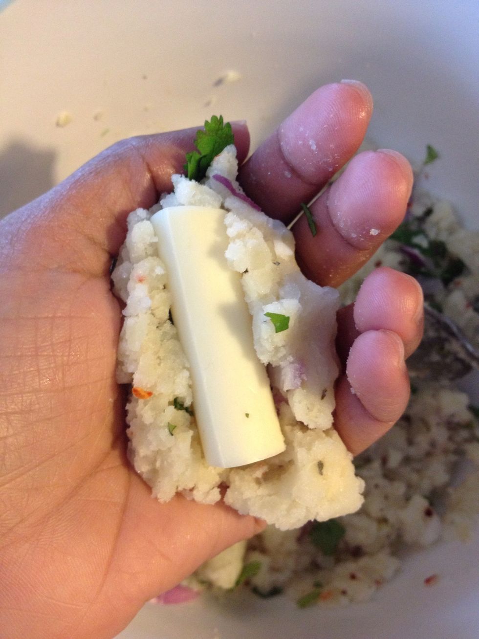 Push in a piece of cheese stick; cover with potato mix