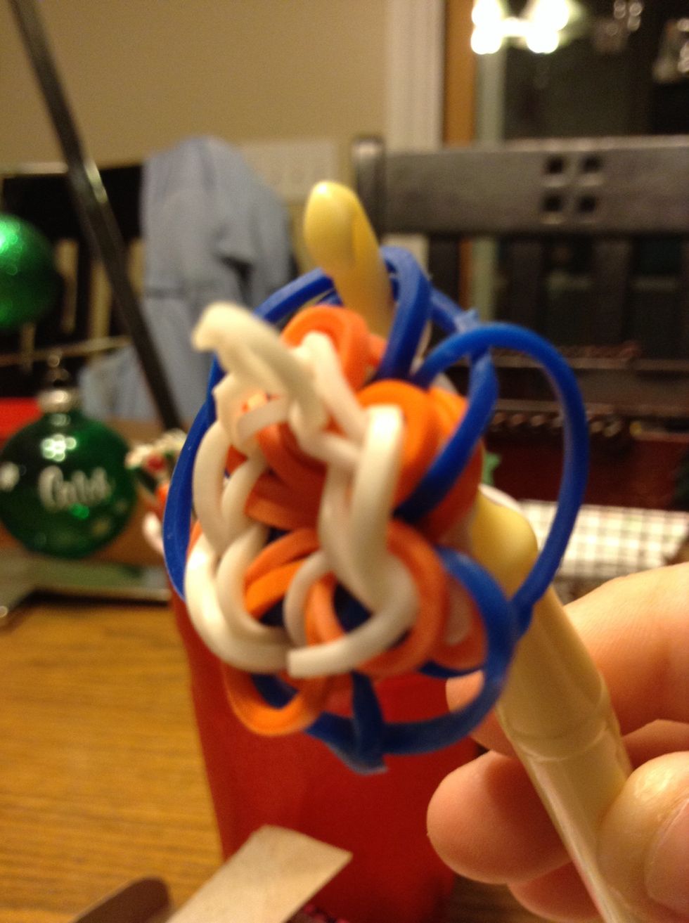 Push the hook through the two blue petals it's by and put the other end of the white band back on the hook.