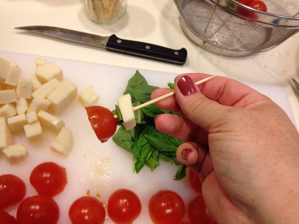 Push the toothpick into a tomato. Push mozzarella and basil down to meet the top of the tomato.