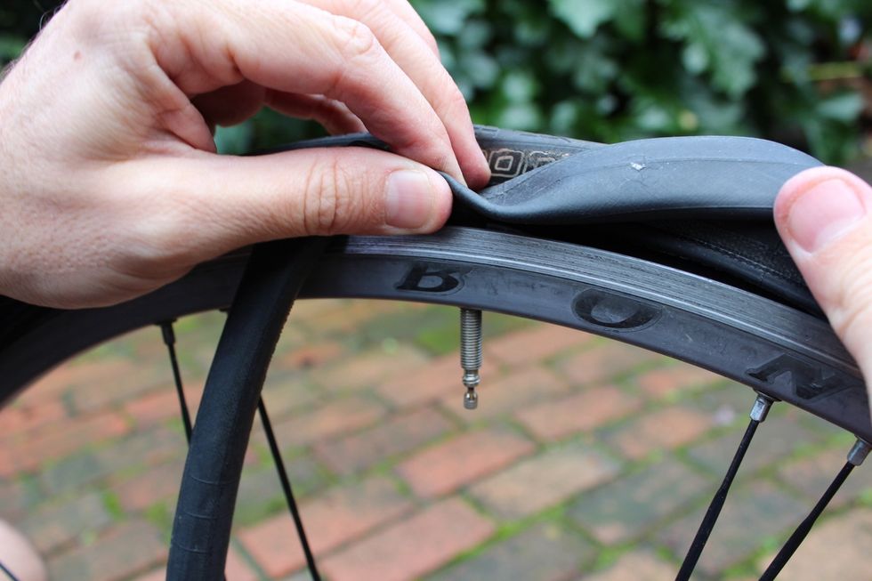 Push the valve stem of the new tube through the hole in the tire and thread the entire tube around the inside of the tire. Avoid twisting the tube by inserting it as flatly as possible.