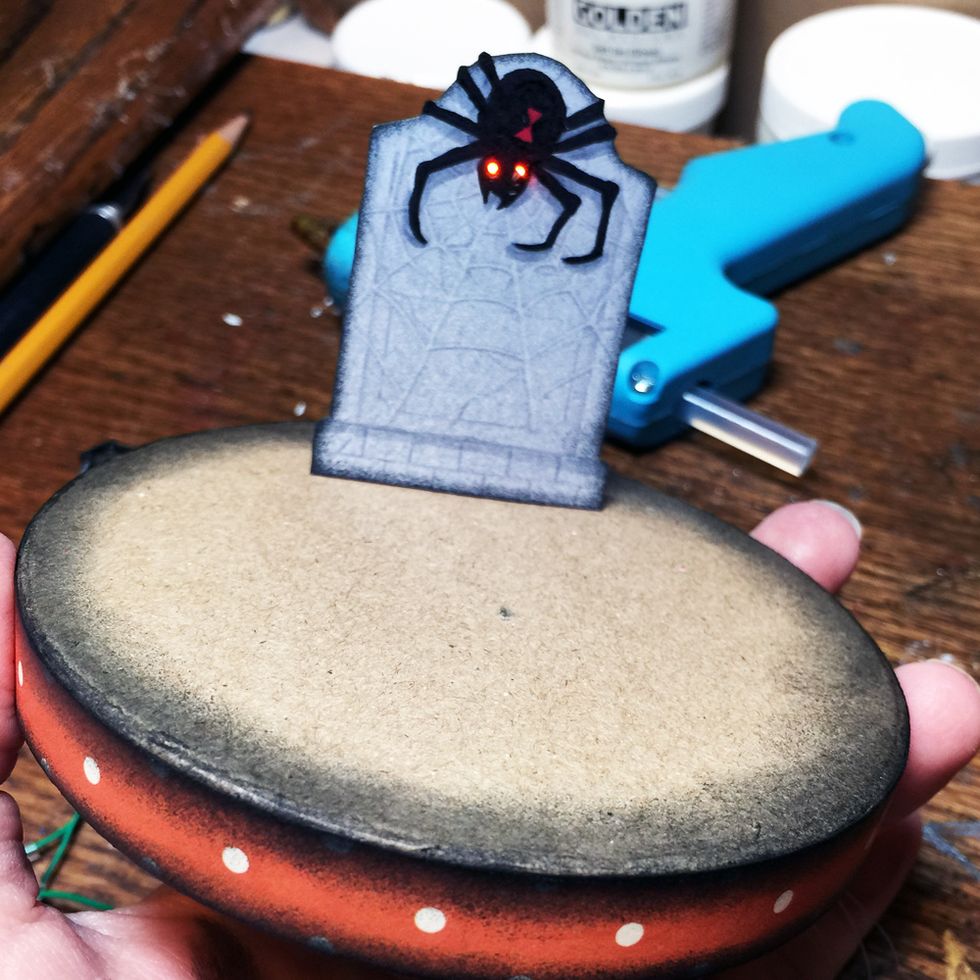 Push the wires back through the hole in the paper mache box then glue your grave stone to the box. There should be a small bit of the matchbox sticking down through the hole in the paper mache box.