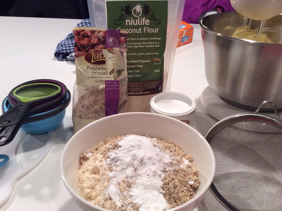 put 1 and a half cups of coconut flour, 100gm of hazelnut meal, and teaspoon of baking powder in a bowl.