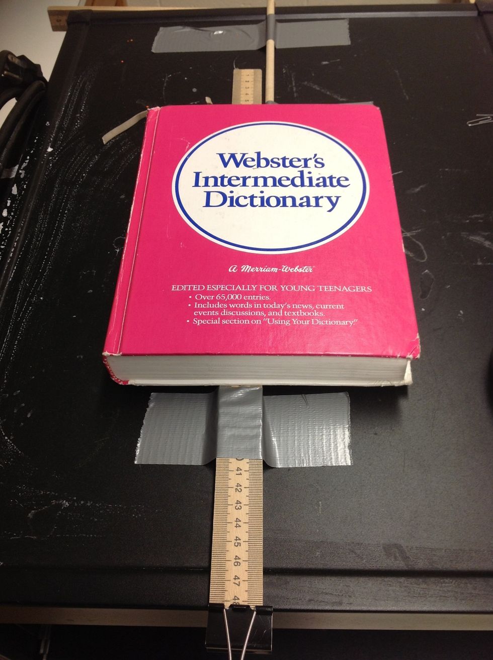 Put a dictionary or other heavy book on the other end of the stick to hold it down.