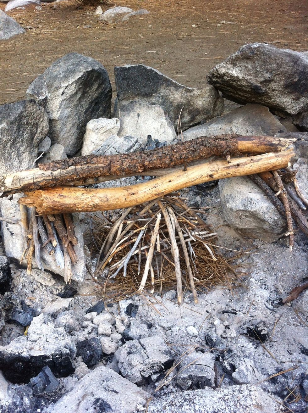 put a few of your largest sized sticks laying across the rocks, and above the pyre.