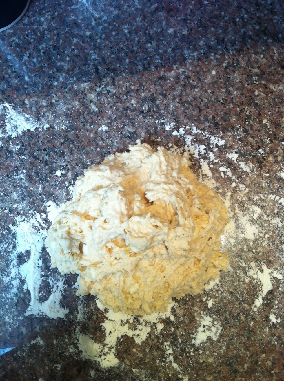 Put a handful of flour on a clean surface and place the dough on top of it. Place another handful of flour on the top of the dough and flip it over.