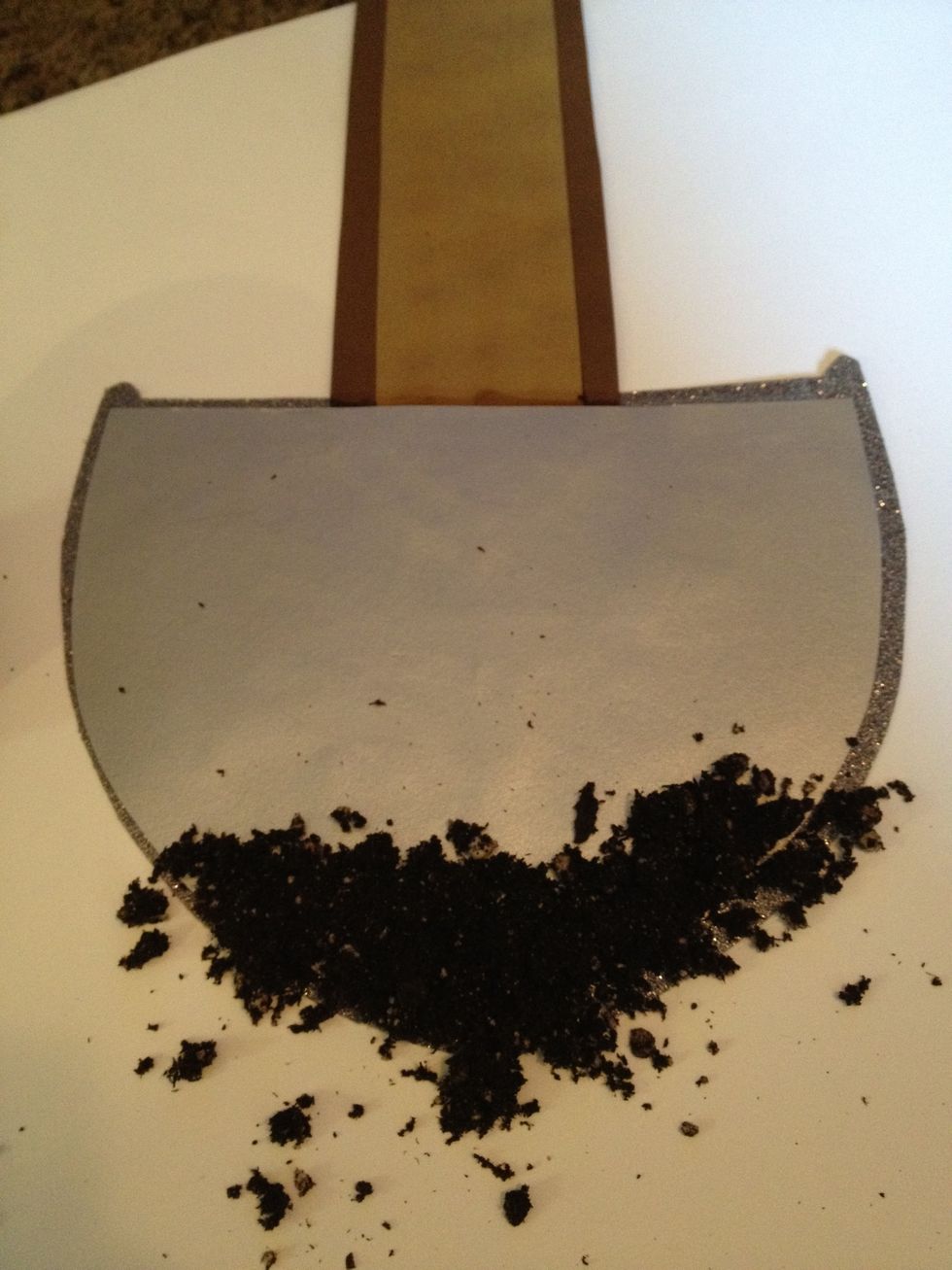 put a lot of glue on the base of the shovel and scatter soil over the glue. don't shake immediately, let it set/dry first.