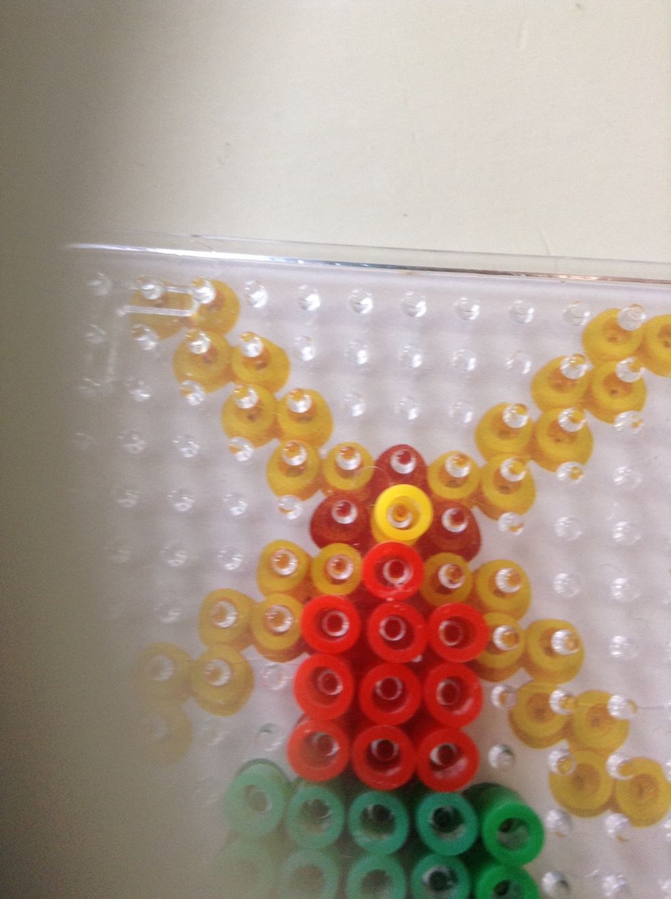Put a red bead down then a yellow bead on top. Put 3 more reds round the yellow.