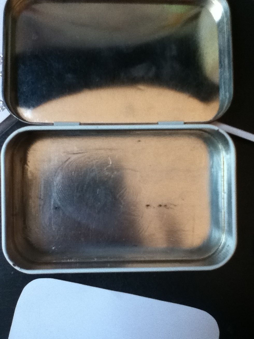 Put a thin layer of double sided tape or glue on the inside bottom of your tin.