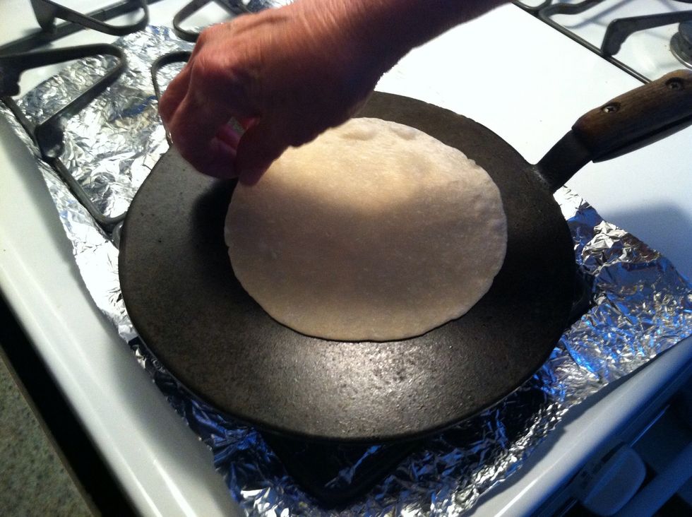 Put a tortilla on the plaquita. When it starts to bubble on the top, turn it over.