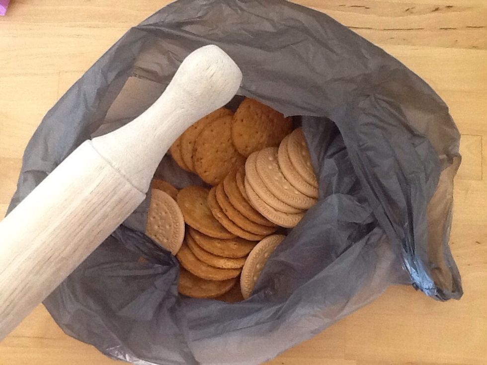 Put all of the biscuits into a plastic bag and bash them up with a rollingpin