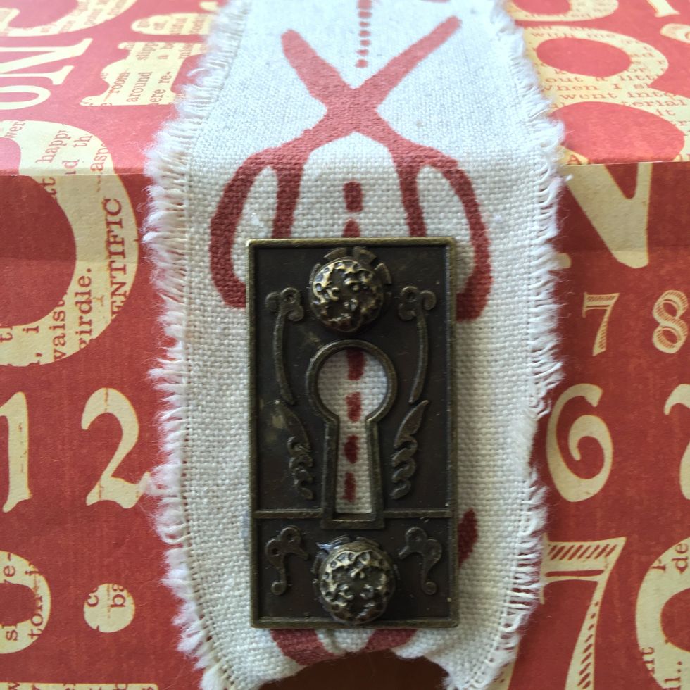 Put an ornate metal key hole on the box front using two brads.
