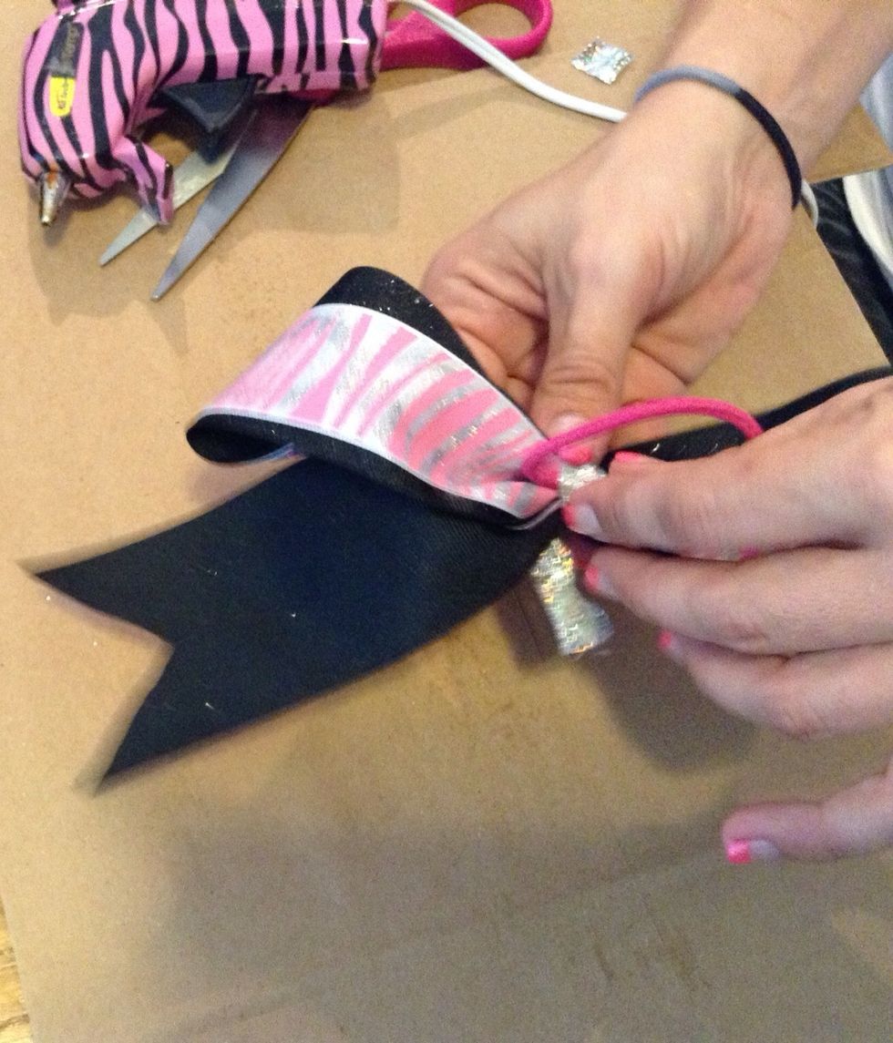 Put another dab of hot glue on the hair tie and wrap the piece of ribbon/fabric around the middle of the bow and secure one end.