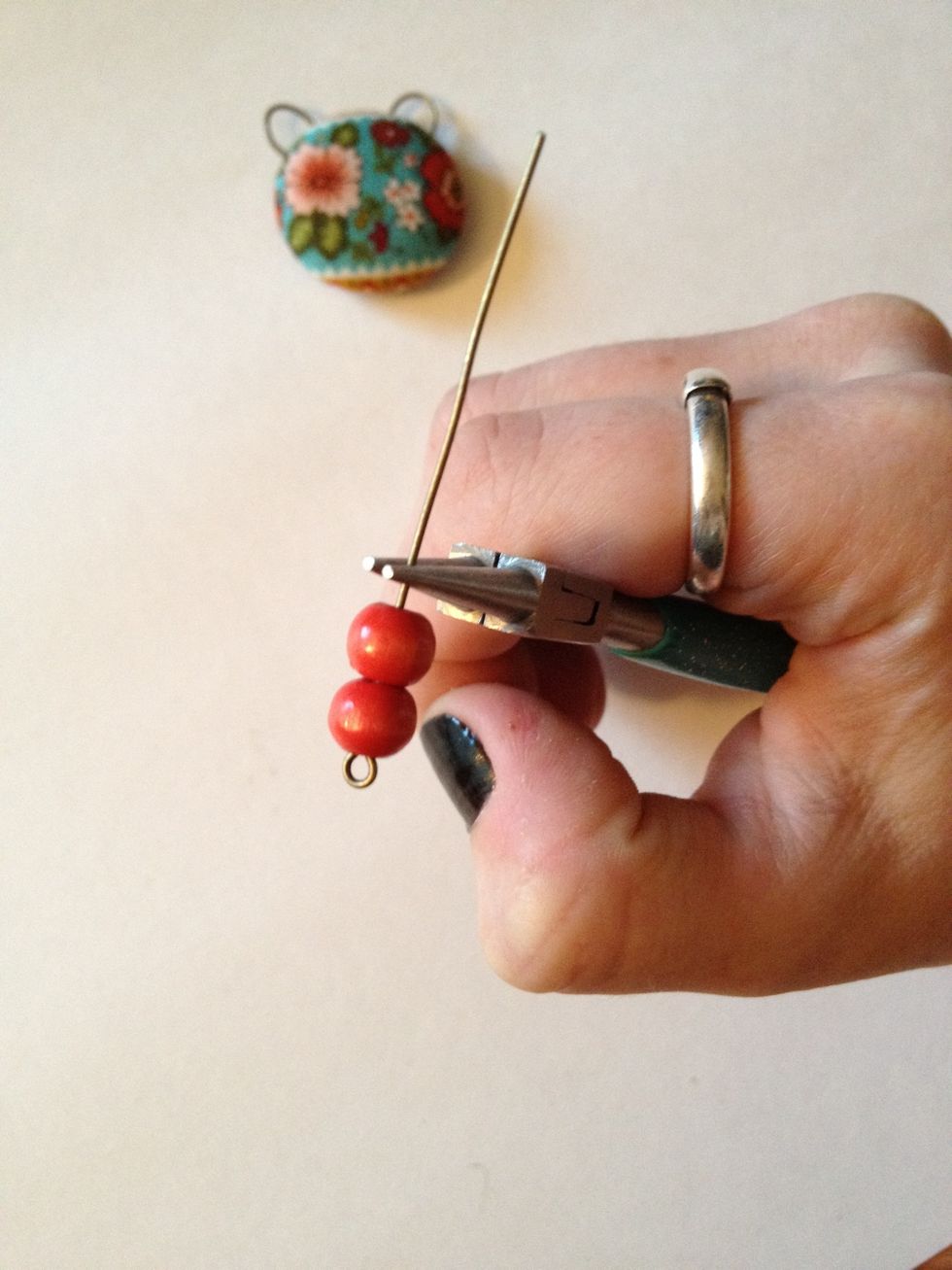 Put bead(s) onto eye pin. Grasp slightly above with needle nose pliers.
