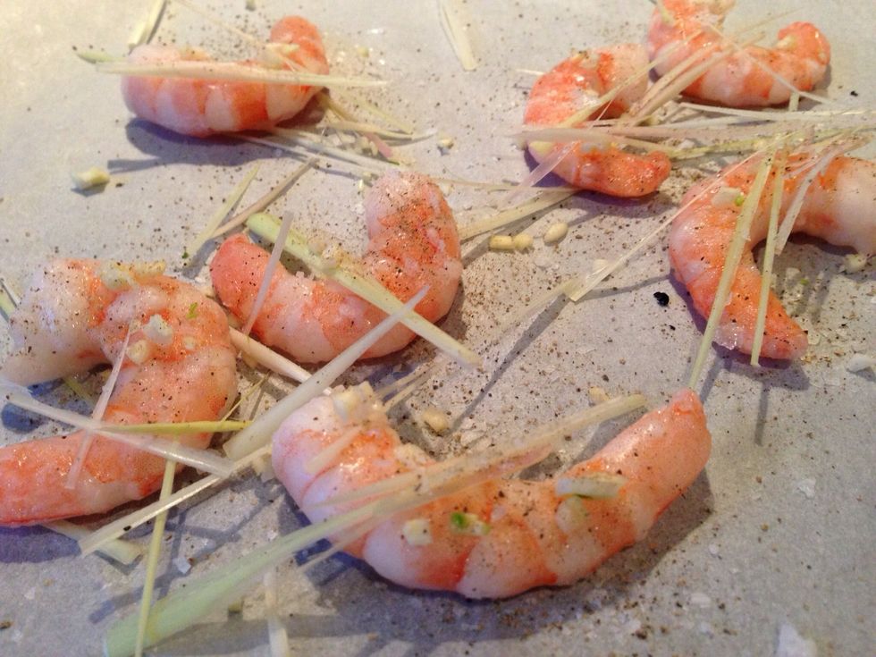 Put eight king prawns on a baking tray, add the rest of the garlic, salt, pepper and the lemon grass stripes.