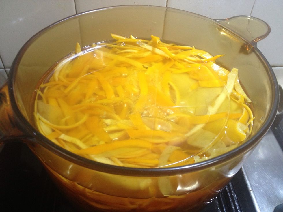 Put equal amounts of water and sugar back in the pan - about 3 1/4 cups each. Boil it, then add orange peels (weigh down oranges with a saucer to keep them submerged throughout next process).