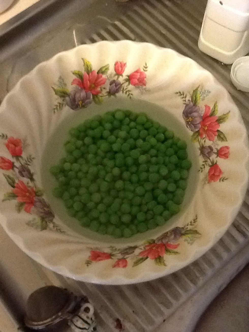 Put frozen peas into a bowl and pour boiled water into the bowl.