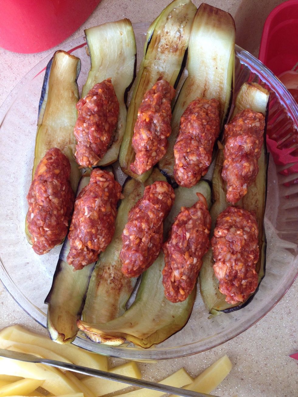 Put half of the eggplants on your tray and place the meatballs on them