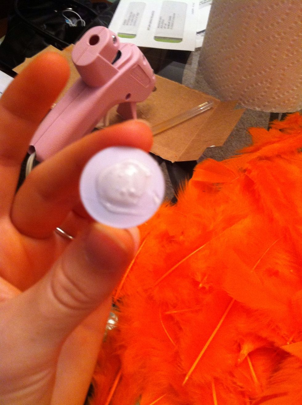 Put hot glue on the back of the wiggly eyes. Be liberal with the glue. Hot glue doesn't always like to stick to feathers.