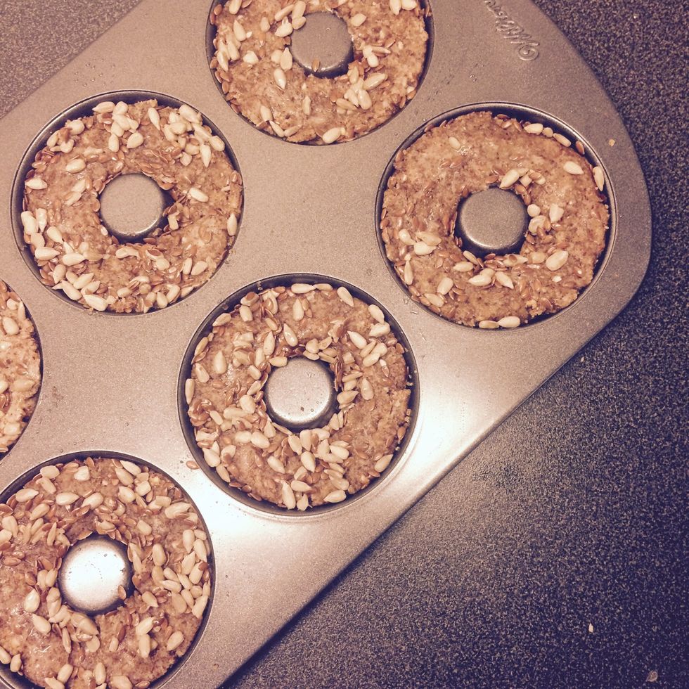 Put into doughnut tray ( greased with a small amount of coconut oil). Use a food-brush to smear the egg white on top of each doughnut. Garnish with mixed seeds.