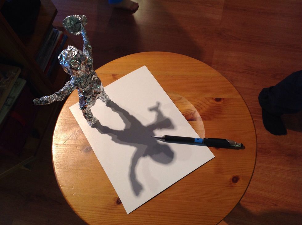 Put it close to a lamp, the shadow will be small and fit the paper. Draw around the shadow.