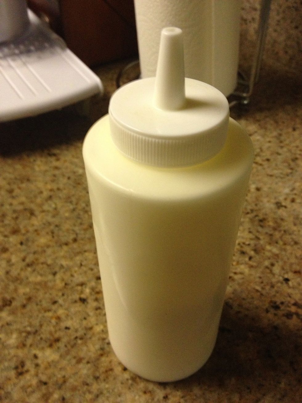 Put it in a squirt bottle or a ziplock bag with the corner cut.  Or use the classic bowl and spoon. Objective=Get sauce on the dough quickly. Squirting sauce on adds for final presentation.
