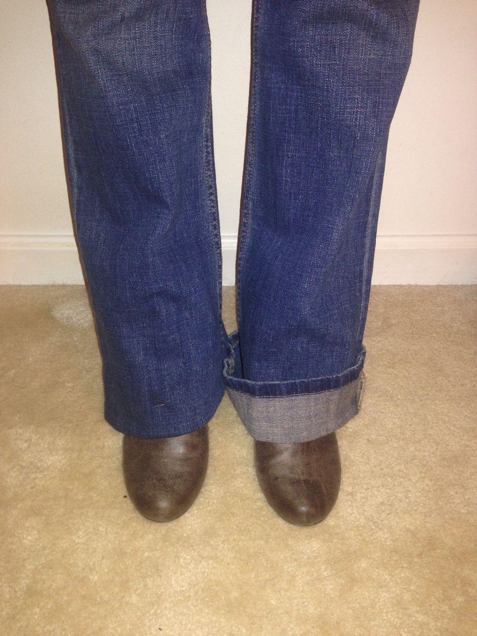Put jeans on with footwear to gauge length adjustment. Fold one leg inward to desired length. Safety pin at inseam to hold fold. Left leg is folded outward to show how much needs chopping.