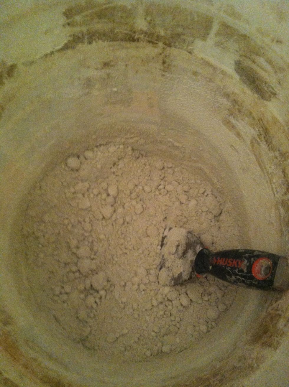 Put mask on, pour grout in bucket and add SOME water. Mix with putty knife. This grout needs more water.