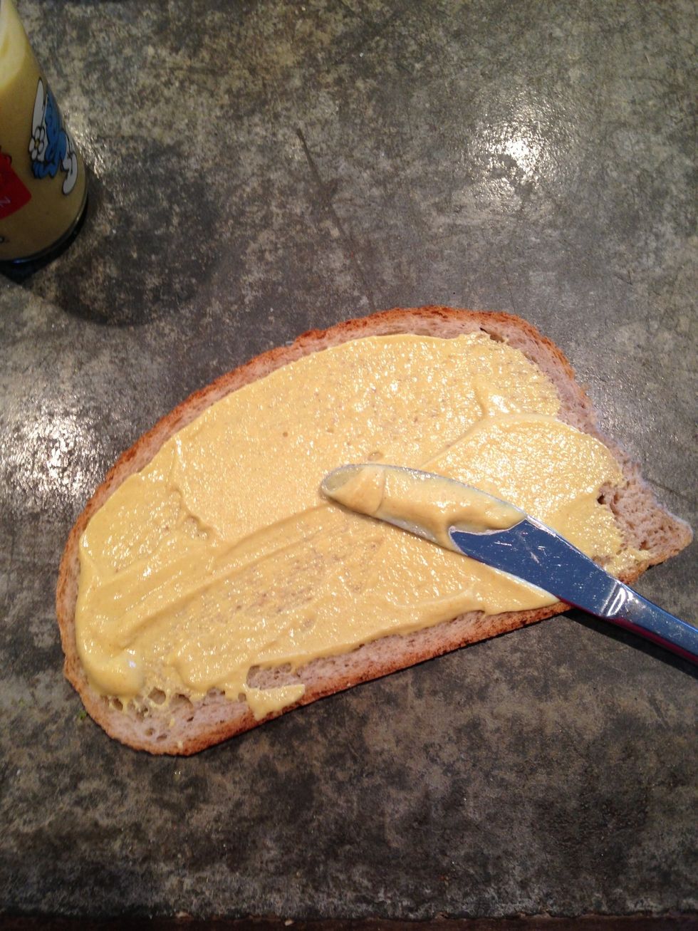 Put mustard on a slice of bread.